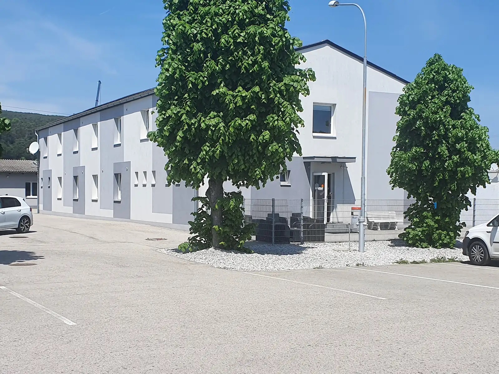 Das Schlafzeit-Gebäude mit Bäumen und Parkplätzen davor