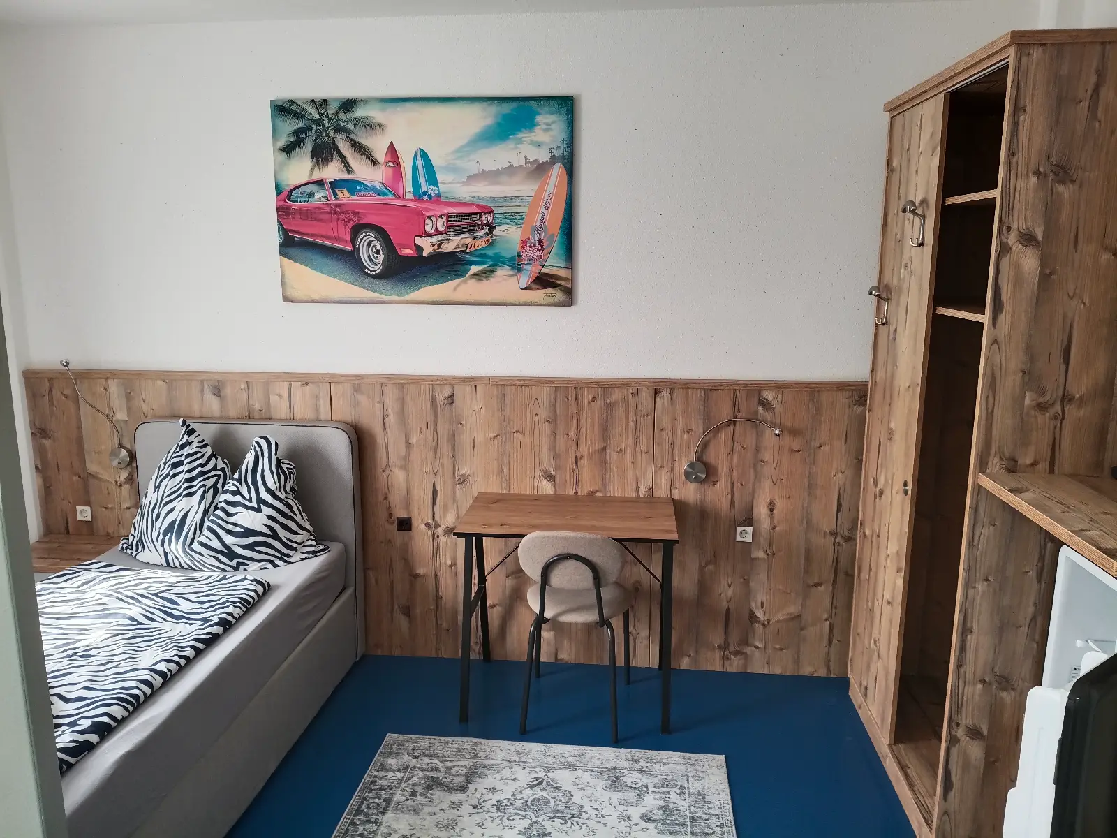 Bett, Schreibtisch, Kleiderschrank und Kühlschrank im Einzelzimmer